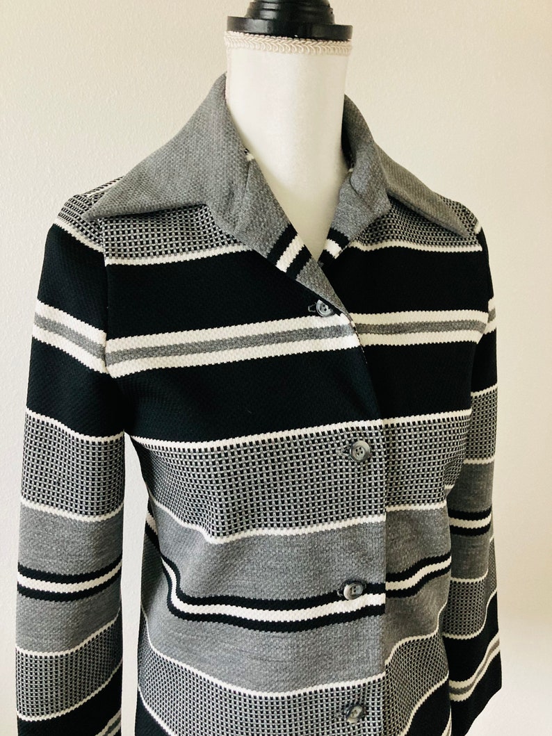 May include: A black and gray striped long-sleeved shirt with a button-up front and a collar.