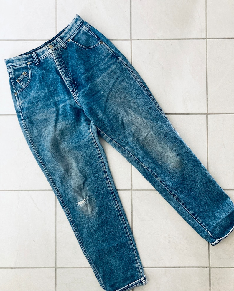 Op de afbeelding: Een lichtblauwe spijkerbroek met een gescheurde knie. De broek heeft een hoge taille en een rechte pijp.