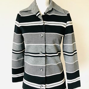 May include: A long-sleeved button-up shirt with a striped pattern in black, white, and gray. The shirt has a collar and a button-up front.