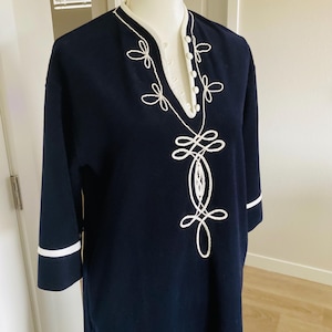 May include: Navy blue tunic with white embroidered detailing. The tunic features a V-neck with white trim and three buttons. The sleeves are three-quarter length with white cuffs. The tunic is displayed on a mannequin.
