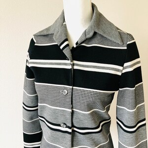 May include: A black and gray striped button-up shirt with a wide collar. The shirt has a textured pattern and is made of a soft, comfortable fabric.
