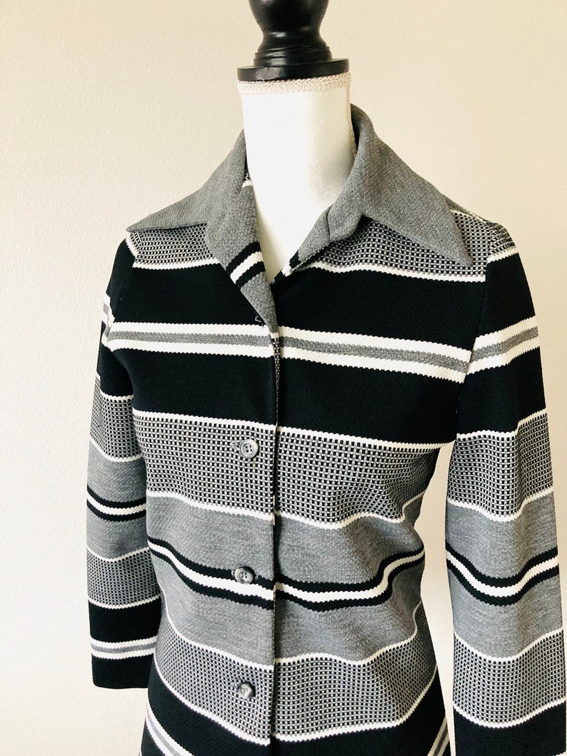 May include: A black and gray striped button-up shirt with a wide collar. The shirt has a textured pattern and is made of a soft, comfortable fabric.