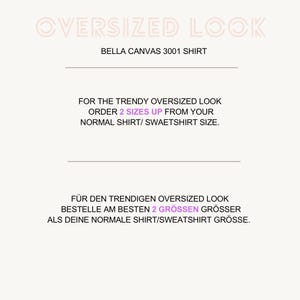 K&ouml;nnte beinhalten: Wei&szlig;es Grafikdesign mit dem Text "OVERSIZED LOOK" in hellrosa Schrift. Darunter steht "BELLA CANVAS 3001 SHIRT." Es wird empfohlen, zwei Gr&ouml;&szlig;en gr&ouml;&szlig;er zu bestellen f&uuml;r einen Oversized-Look.