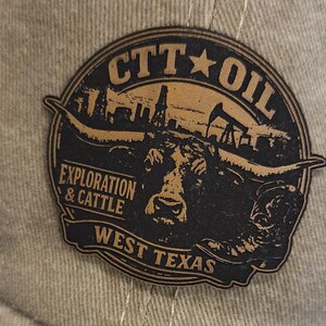 May include: A beige baseball cap with a brown leather patch. The patch displays the text "CTT OIL" above an illustration of a longhorn, oil derricks, and the words "EXPLORATION & CATTLE WEST TEXAS".