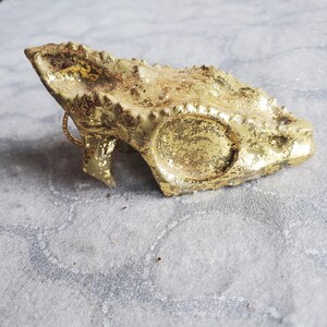 以下が含まれることがあります： 金色の塗装が施された、ドラゴンヘッドの形をしたセラミック製のオーナメント。オーナメントは、テクスチャ加工された表面と、詳細なデザインが施されています。