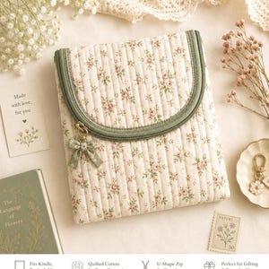 Può includere: Una custodia in tessuto trapuntato con sfondo color crema e un piccolo motivo floreale rosa. La custodia presenta una chiusura a zip a forma di U color verde salvia e un fiocco in tessuto verde salvia abbinato attaccato al cursore della zip.