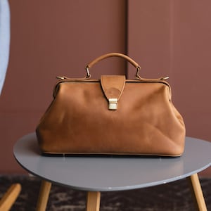 May include: A brown leather doctor's bag with a brass clasp and handle.