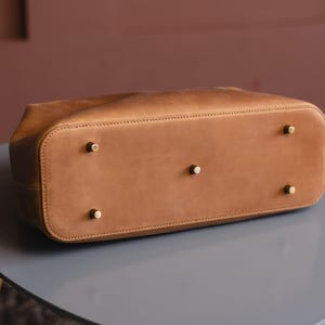 May include: The bottom of a brown leather tote bag with four brass studs.
