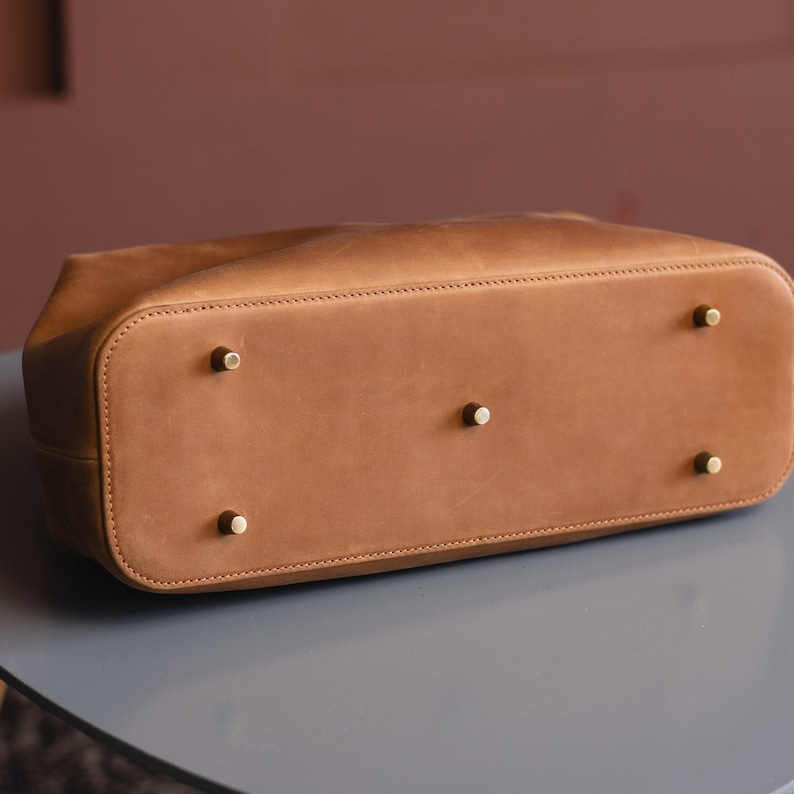 May include: The bottom of a brown leather tote bag with four brass studs.