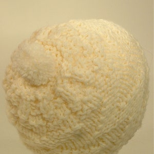 May include: A white knitted beanie with a fluffy pom-pom on top.