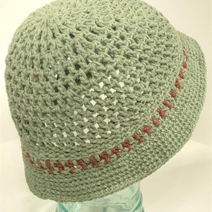 May include: A green crocheted hat with a brown trim. The hat is made with an open stitch pattern.