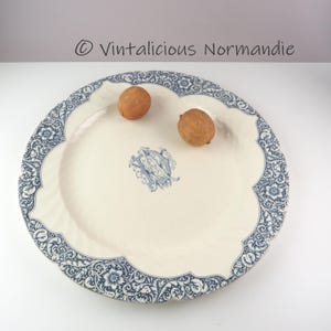 May include: A large, white ceramic serving platter with a blue and white floral pattern around the edge. The centre of the platter features a blue and white monogram.