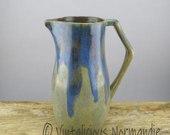 May include: A blue and green ceramic pitcher with a unique handle. The pitcher has a drip glaze effect.
