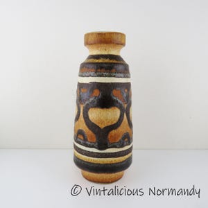 May include: A brown and white ceramic vase with a geometric pattern. The vase has a wide base and a narrow neck.