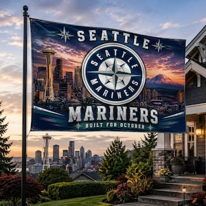 Könnte beinhalten: Eine große Flagge mit dem Logo der Seattle Mariners und der Skyline der Stadt. Auf der Flagge stehen die Worte "SEATTLE MARINERS" und "BUILT FOR OCTOBER". Der Hintergrund zeigt einen Sonnenuntergang über der Stadt und einem Berg.