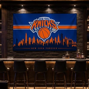 May include: A rectangular wall banner featuring the New York Knicks logo in blue and orange, with a basketball graphic and a silhouette of the New York City skyline. The text NEW YORK KNICKS is displayed above the basketball, with NEW YORK FOREVER below.