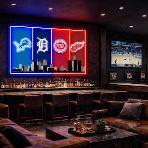 May include: A large rectangular neon wall sign featuring the logos of the Detroit Lions, Tigers, Pistons, and Red Wings over a black city skyline silhouette. The sign is divided into blue and red vertical panels, mounted on a dark wall.