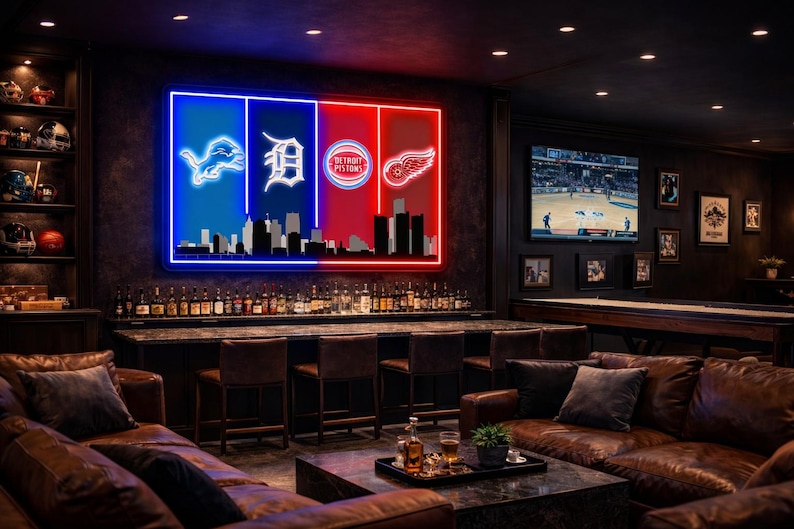 May include: A large rectangular neon wall sign featuring the logos of the Detroit Lions, Tigers, Pistons, and Red Wings over a black city skyline silhouette. The sign is divided into blue and red vertical panels, mounted on a dark wall.