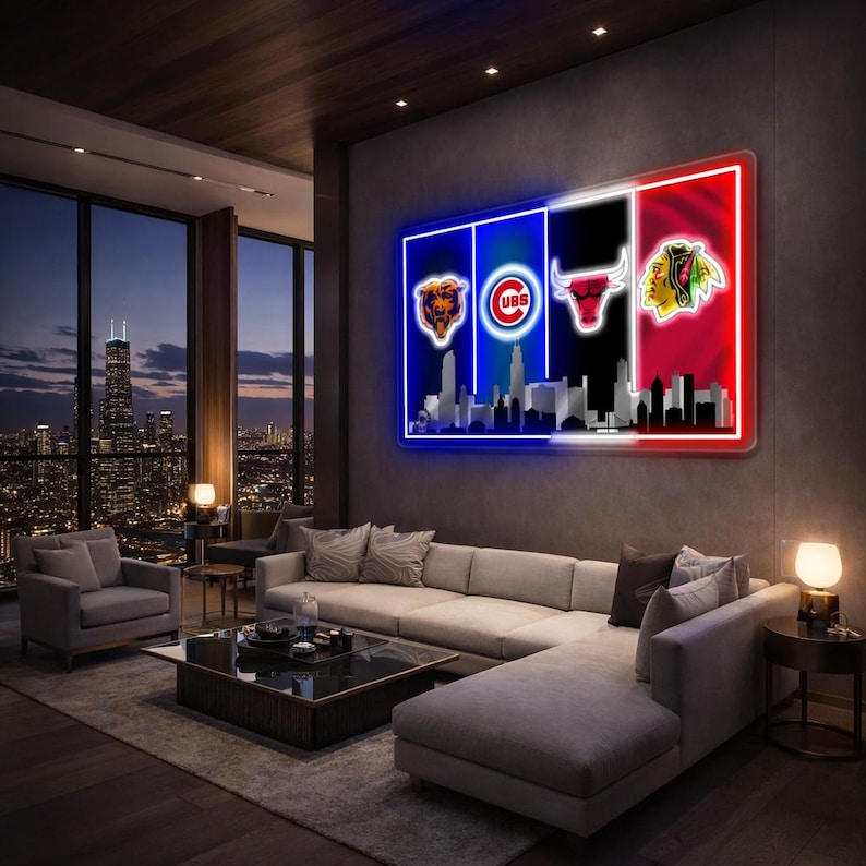 May include: A large, illuminated wall art piece featuring the logos of the Chicago Bears, Cubs, Bulls, and Blackhawks. The artwork is divided into sections with the team logos and a skyline silhouette. The piece is mounted on a dark grey wall in a modern living room.