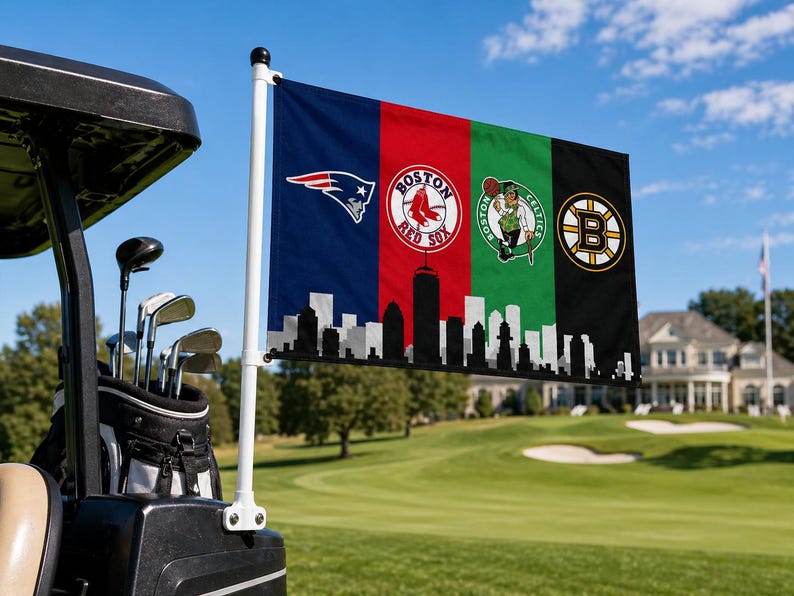 Pode incluir: Uma bandeira com os logotipos dos New England Patriots, Boston Red Sox, Boston Celtics e Boston Bruins. A bandeira est&aacute; presa a um carrinho de golfe em um campo de golfe. A parte inferior da bandeira tem um horizonte em preto e branco.