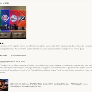 May include: A rectangular wall sign featuring four vertical panels with illuminated Philadelphia sports team logos above a black silhouette of the city skyline. The panels are backlit with green, blue, red, and orange LED lighting.