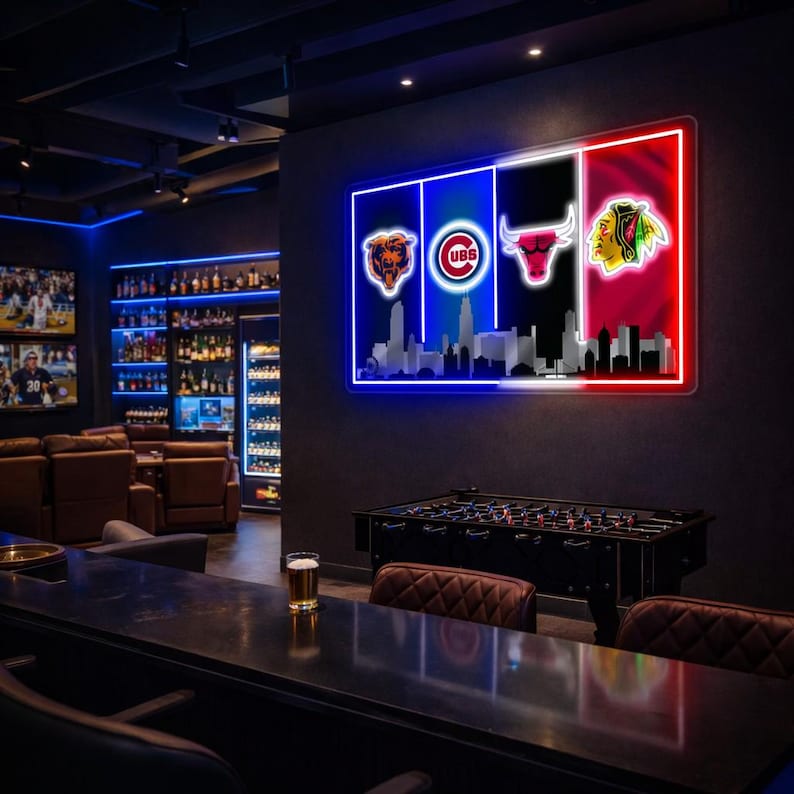 May include: A rectangular wall-mounted neon sign featuring the Chicago Bears, Cubs, Bulls, and Blackhawks logos arranged horizontally above a silhouette of the Chicago skyline, illuminated in vibrant blue, white, black, and red neon light tubes.