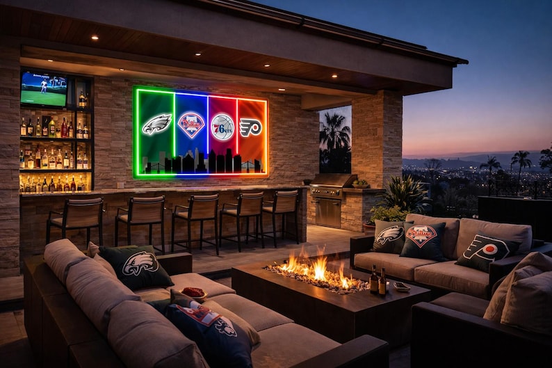 May include: Outdoor entertainment area with a bar, seating, and a fire pit. A neon sign displays logos of Philadelphia sports teams. The scene is illuminated by warm lighting, with a view of the city at dusk.