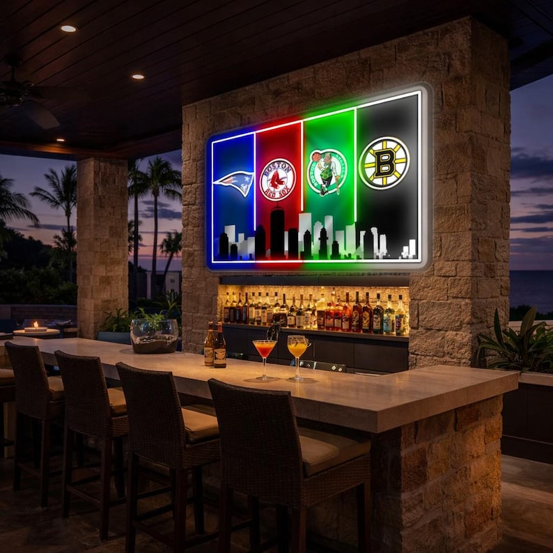 May include: A rectangular LED wall sign featuring four vertical panels in blue, red, green, and black. Each panel displays a sports team logo, including the New England Patriots, Boston Red Sox, Boston Celtics, and Boston Bruins above a city skyline.
