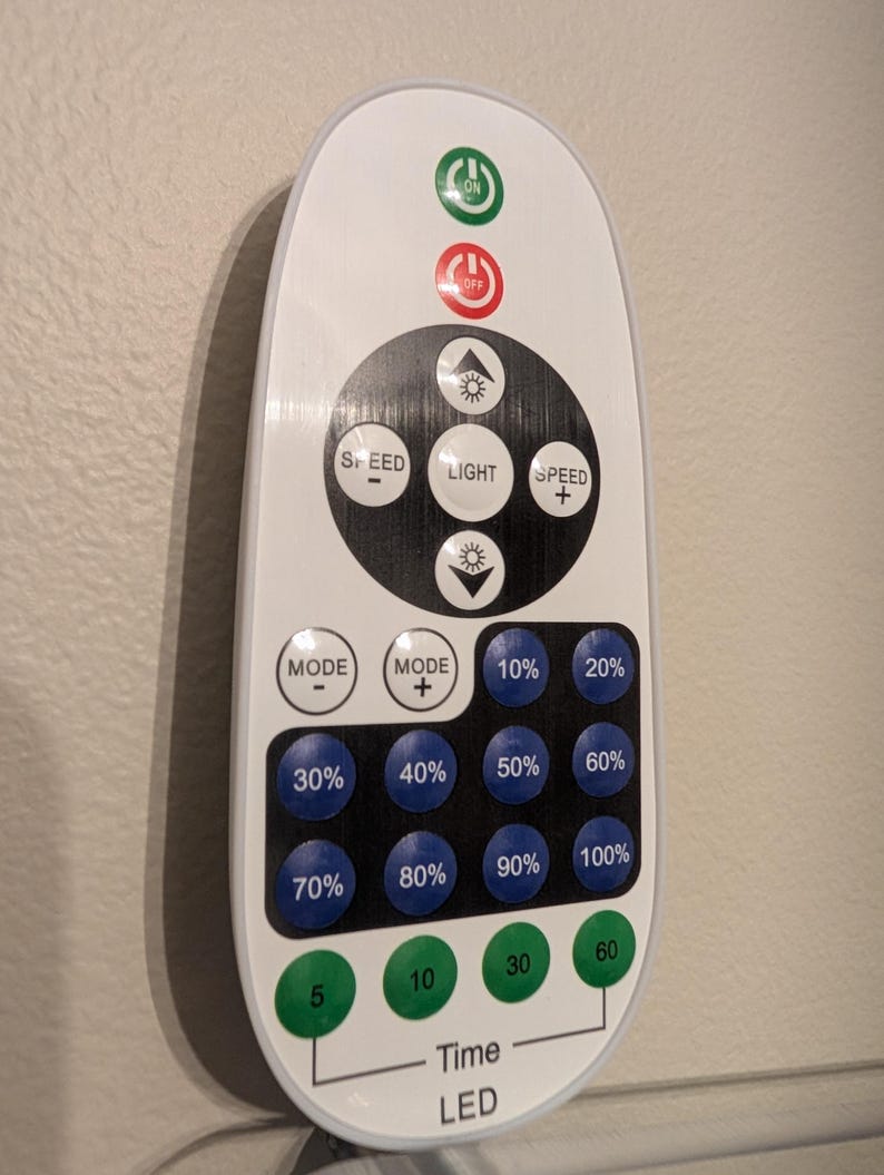 May include: A white remote control with a black circular control pad featuring buttons for light, speed, and mode. It includes blue buttons labeled 10% through 100% for brightness, green timer buttons labeled 5, 10, 30, 60, and red and green power buttons.