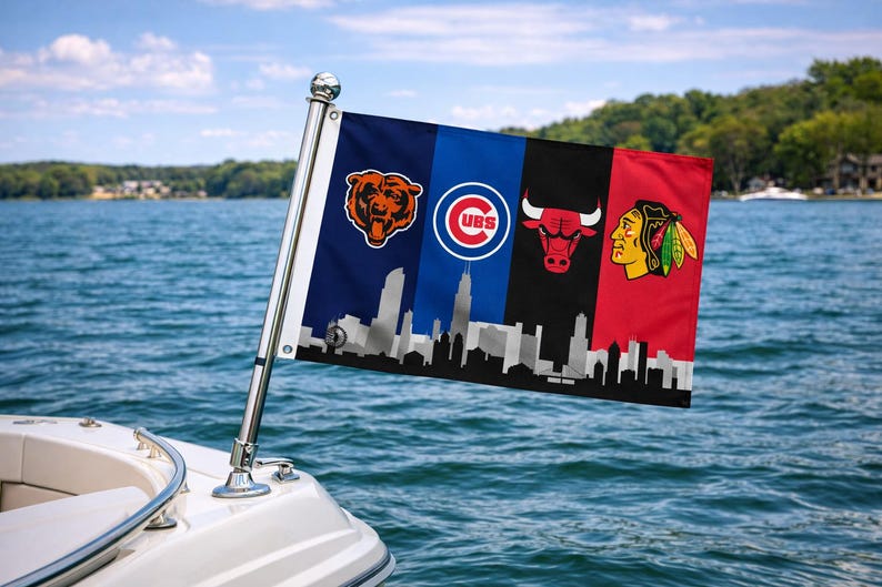 May include: A flag displaying the logos of the Chicago Bears, Cubs, Bulls, and Blackhawks, with a city skyline silhouette. The flag is attached to a boat, set against a backdrop of a lake and trees.
