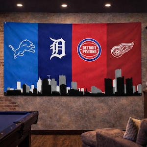 May include: A large wall flag featuring the logos of Detroit sports teams: Lions, Tigers, Pistons, and Red Wings. The flag is divided into four sections with a black and white skyline silhouette at the bottom. The flag is displayed in a bar setting.