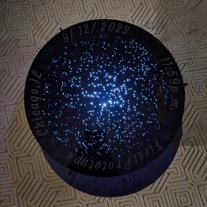 May include: A black circular star map with a blue light shining through the center. The map shows the night sky as it appeared on September 12, 2023 at 11:59 pm in Chicago, Illinois. The text "T.I.V.S.T.P. Prototype" is written around the edge of the map.