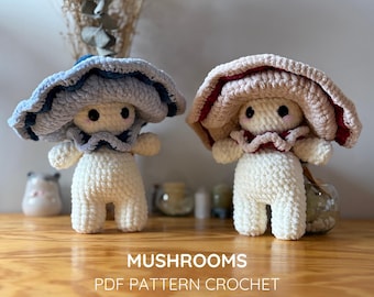 May include: Two crocheted mushroom dolls with white bodies and wide, ruffled caps. One cap is light blue with dark blue accents, and the other is beige with deep red accents. The text MUSHROOMS PDF PATTERN CROCHET ENG/ESP is printed below.
