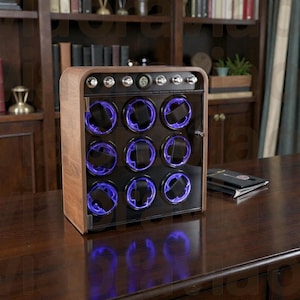 May include: A wooden watch winder with a glass door, featuring nine watch holders illuminated by blue lights. The winder has a digital display and is set on a dark wooden surface.