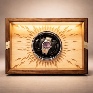 May include: A wooden watch winder with a light-coloured interior and a dark wood frame. The winder features a gold-toned watch with a purple face, set against a black leather cushion. The interior has a sunburst design.