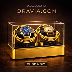 May include: A gold watch display case with two watches inside. The case has a clear top and a gold base. The watches have gold and silver straps and are displayed on gold holders. The text "EXCLUSIVELY AT ORAVIA.COM" and "SHOP NOW" are visible.