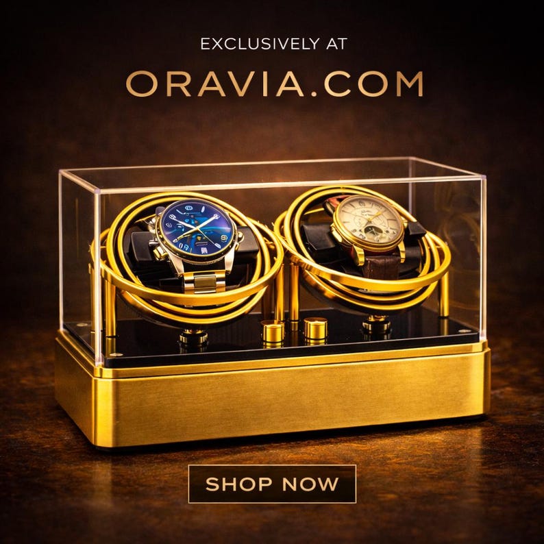 May include: A gold watch display case with two watches inside. The case has a clear top and a gold base. The watches have gold and silver straps and are displayed on gold holders. The text "EXCLUSIVELY AT ORAVIA.COM" and "SHOP NOW" are visible.
