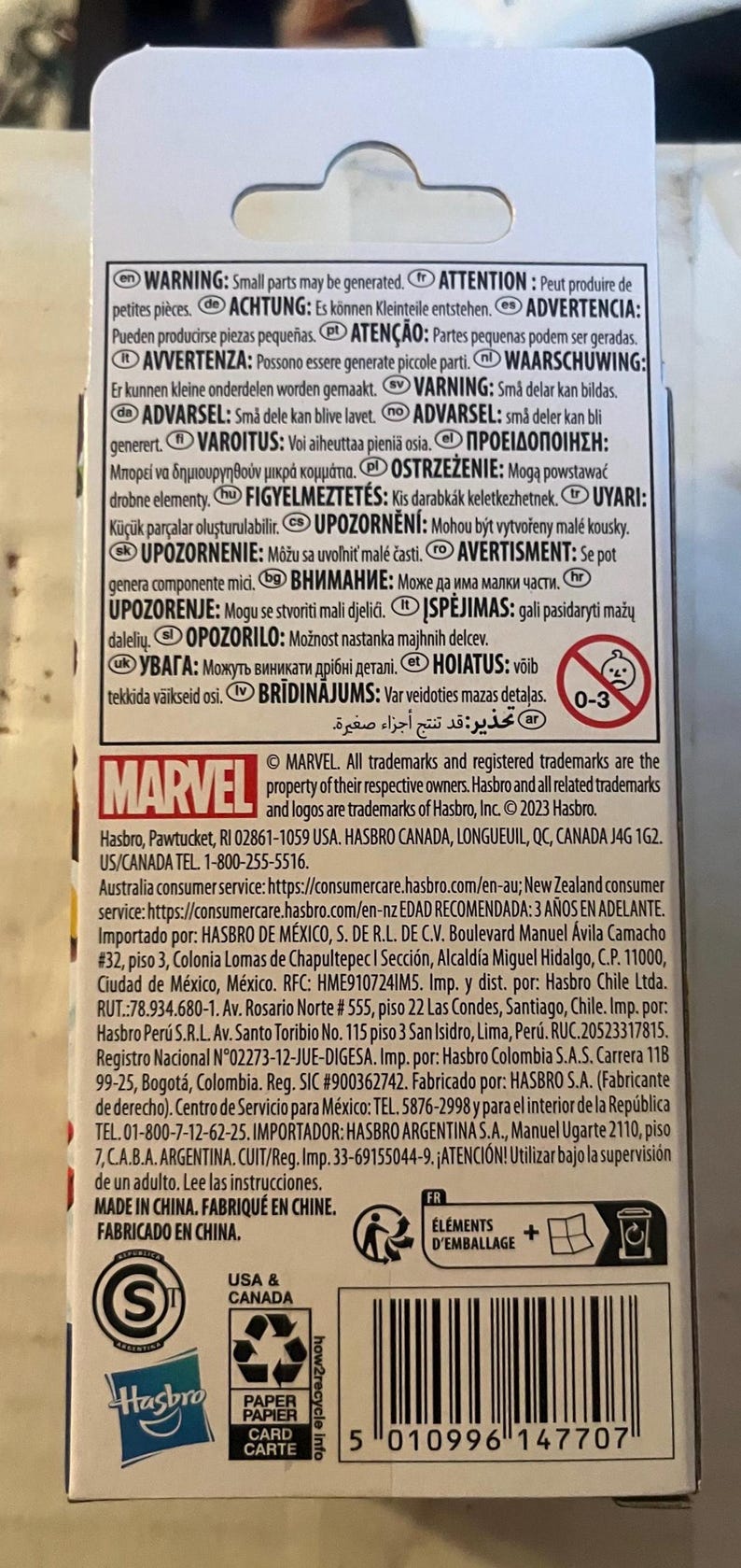 May include: A product package with the Marvel logo, warnings in multiple languages, and a recycling symbol. The package includes text in English, French, and Spanish. The age range is 0-3.