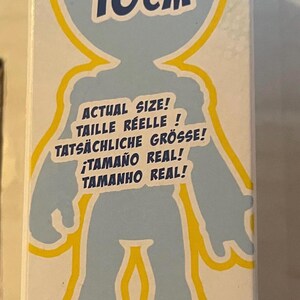 May include: A product box with a light blue silhouette of a person, outlined in yellow. The text on the box indicates the actual size is 4 inches / 10 cm. Additional text includes "Actual Size!" in multiple languages.
