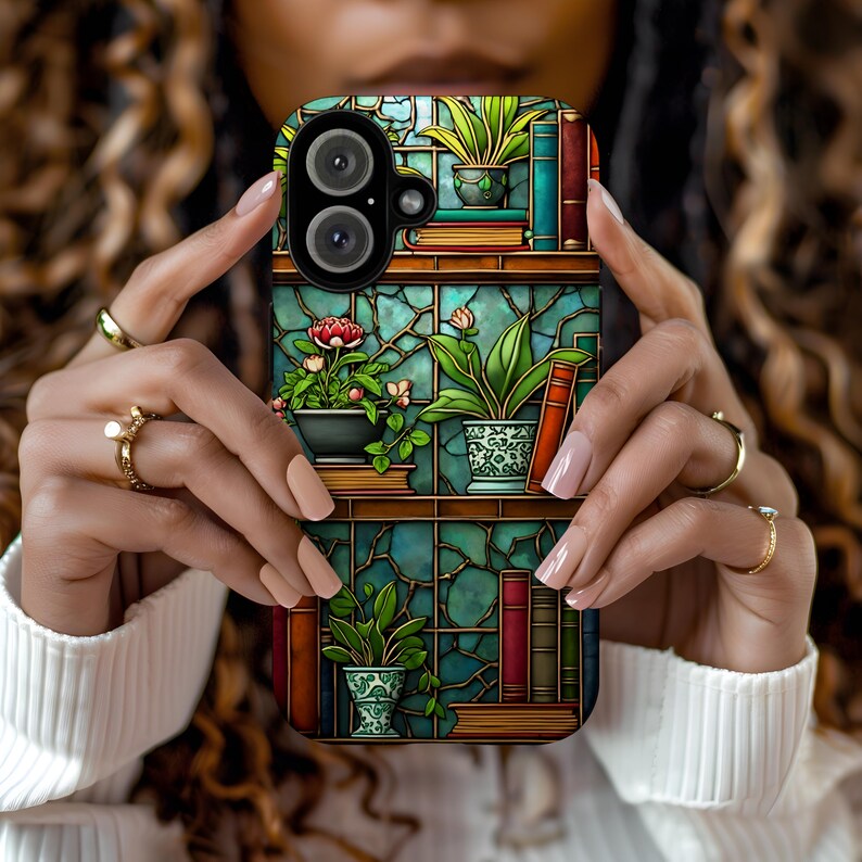 iPhone case with an intricate stained glass-style design featuring bookshelves adorned with potted plants, blooming flowers, and colorful books. The background showcases a rich teal mosaic pattern, creating a warm, vintage-inspired botanical library look.