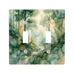 May include: A square double light switch wall plate featuring an abstract forest scene with watercolor-style green and beige ink washes, gold vein accents, and fern silhouettes. The plate has four silver screws and two rectangular cutouts.