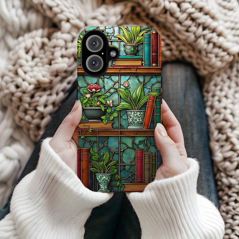 May include: A phone case featuring a colorful design of a bookshelf with potted plants and books. The case has a teal background with a stained glass effect. The plants include a red rose and various green plants.