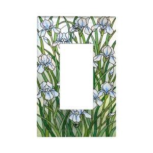 May include: A decorative light switch cover featuring a stained glass design. The cover is adorned with white and light blue iris flowers and green leaves. The floral pattern surrounds the rectangular opening for the switch.