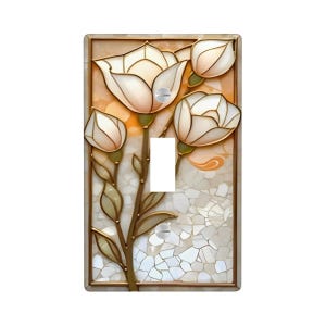 May include: Decorative light switch cover featuring a floral design with white and cream-colored flowers and buds. The switch plate has a mosaic background and a gold-colored frame. The toggle switch is white.