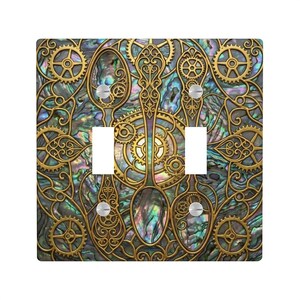 May include: A decorative double light switch cover with a steampunk design. The cover features a gold-colored filigree design with gears and spoon-like shapes over an iridescent background. The cover has two switch openings and two screws.