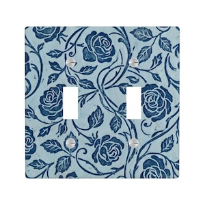 May include: A light blue double light switch cover with a dark blue floral rose pattern. The design features roses, leaves, and vines. The cover has two switch openings and is secured with silver screws.