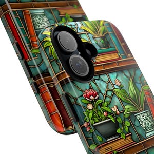 May include: A smartphone case featuring a stained-glass design with a library theme. The case showcases shelves of books, potted plants, and a vibrant color palette of teal, red, and green. The phone's camera lenses are visible.