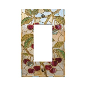 May include: Decorative light switch cover with a stained glass design. The cover features a cherry branch with red cherries, green leaves, and gold-colored accents. The background is a mix of light colors.