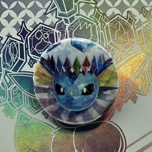 Botón holográfico de Vaporeon: reciclado a partir de paquetes de cartas Pokémon de Prismatic Evolutions