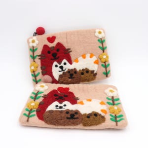 May include: Two light pink felt pouches with embroidered cat and hedgehog designs. The pouches feature red cats, white hedgehogs, and brown hedgehogs, with floral accents. One pouch has a red ball zipper pull.